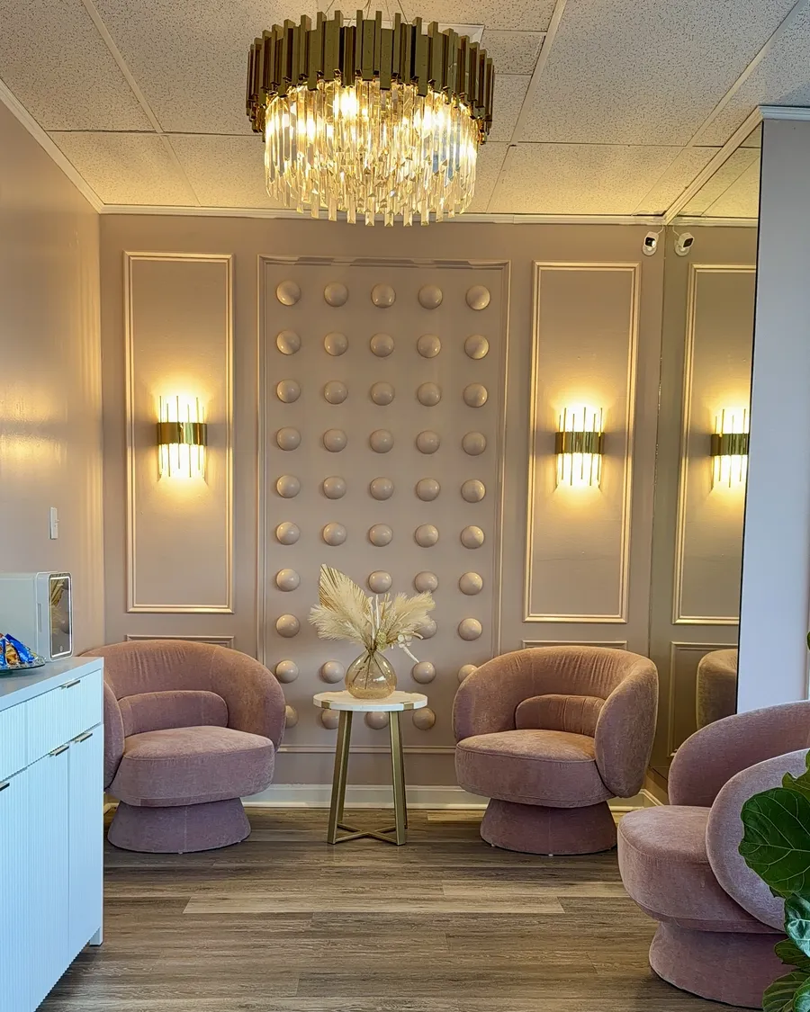 Lounge of the Wilmington, MA studio with a crystal chandelier, sconces and blush velvet chairs