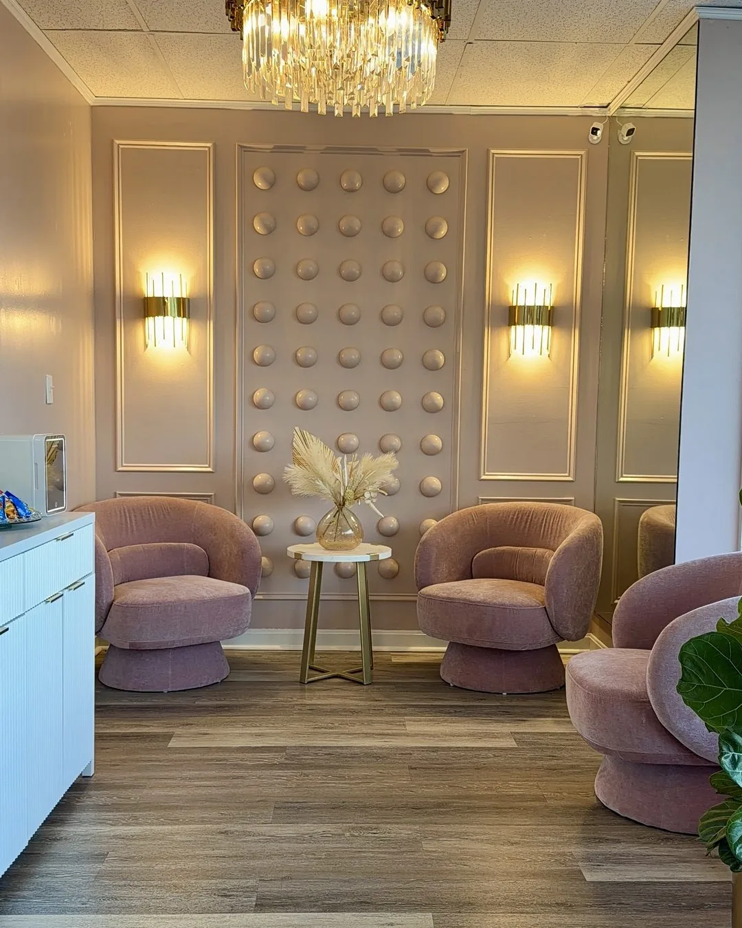 Waiting room at the Wilmington, MA permanent makeup studio, with blush armchairs and a gold chandelier